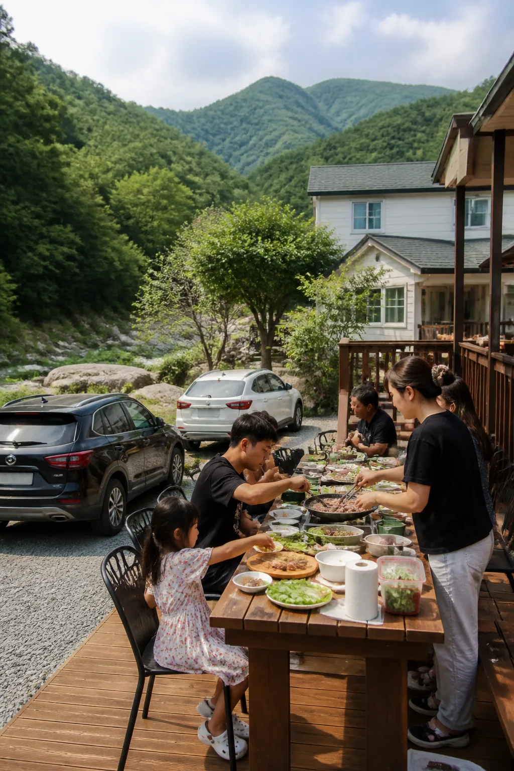 산과 계곡을 배경으로 여러 명이 바비큐를 준비하는 강원도펜션 모임 여행